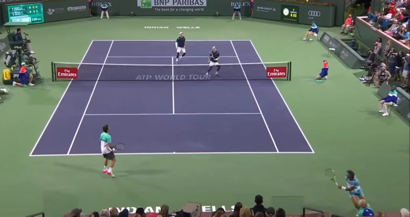 Tennis doubles match at Indian Wells, with players from both teams positioned for the next shot, preparing to return a volley